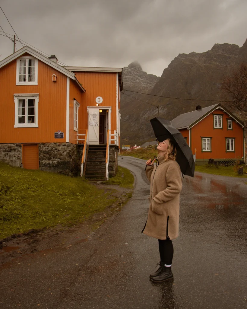 Vanessa von Be a Hyggespreder mit Schirm vor orangenen skandinavischen Häusern