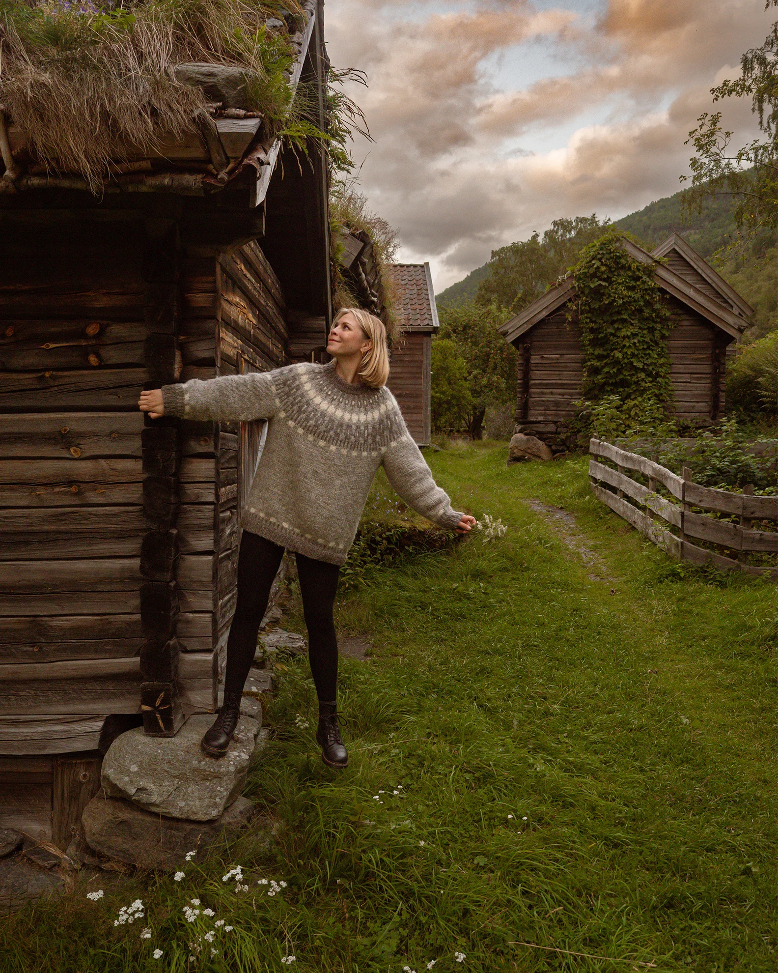 Vanessa von Be a Hyggespreder vor einem Holzhaus in einem grauen Norwegen-Pullover